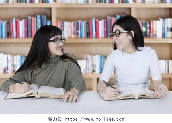 两个女学生一起在图书馆学习